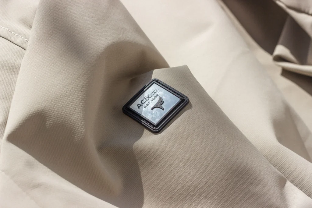 Zbliżenie na beżowy materiał z widocznym logo AC&Co, idealne do treści modowych.